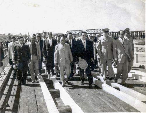 Comitiva de autoridades mexicanas sobre el puente improvisado de madera sobre el Rio Bravo entre ambos Laredos. Ca. 1955.
