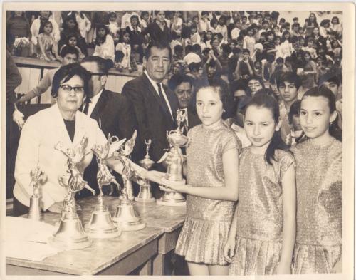 La Profra. Epigmenia Galarza entrega un trofeo a niñas de la Esc. Carlos A. Carrillo durante la celebración del concurso de rondas y juegos infantiles de 1970.