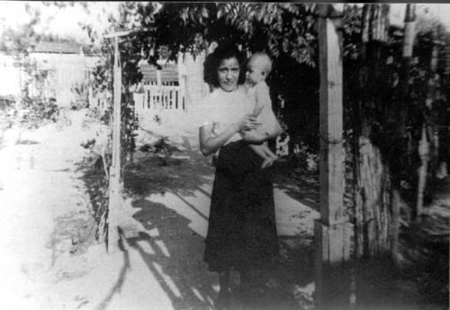 Mujer cargando a un bebe en un jardín familiar de Nuevo Laredo. Década de 1940.