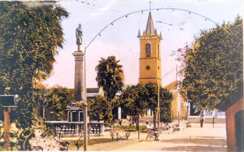 Tarjeta postal coloreada con la imagen de la Plaza Juárez y el Templo del Santo Nino al fondo. Principios del siglo XX.